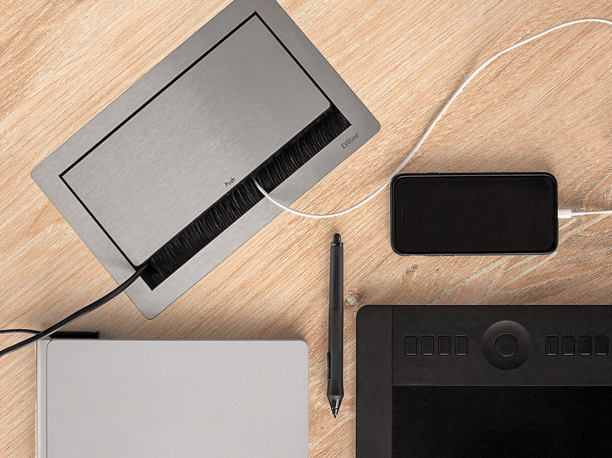 Modulare Stromversorgung für den Konferenztisch für hybride Meetings Konferenzsteckdose FlipTop Push eingebaut. Eingesteckte Kabel bleiben im geschlossenem Zustand eingesteckt.